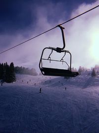 Ski lift over snow covered field against sky