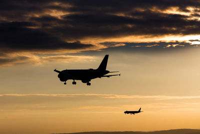 Low angle view of silhouette airplane against sky during sunset