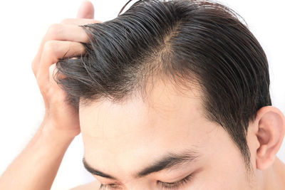 Cropped image of man with hand in hair against white background