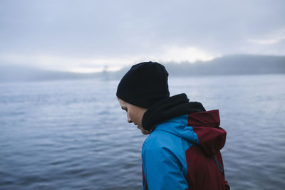 Side view of man looking at sea against sky