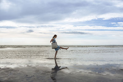 Girl with bag playing in water at beach