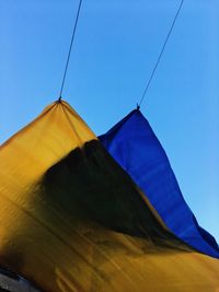 Low angle view of flags against clear blue sky