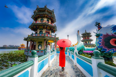 Asian woman wearing cheongsam traditional red dress standing on bridge 