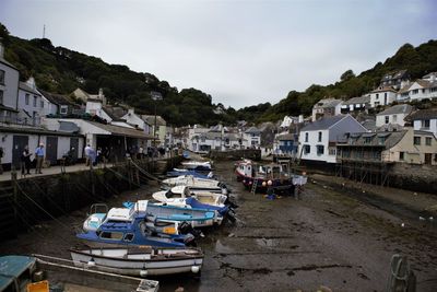 Boats moored on houses by buildings in town against sky