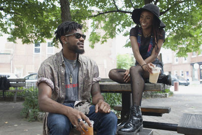 A young man and a young woman at a picnic table with iced coffee.