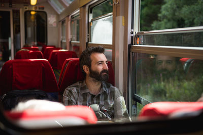 Smiling passenger looking through window while sitting in bus