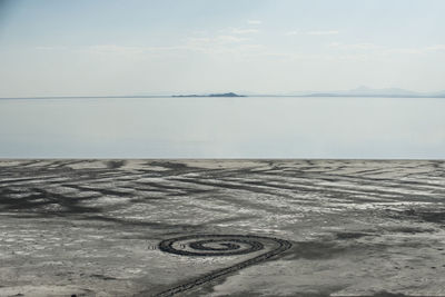 High angle view of spiral pattern on sand by great salt lake against sky