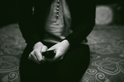 Midsection of woman sitting on bed