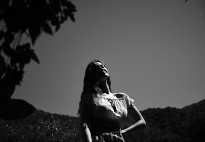 Low section of woman standing on field against clear sky