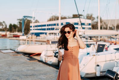 Portrait of young woman in sunglasses standing on boat