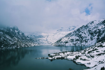 Scenic view of frozen lake by mountains against sky