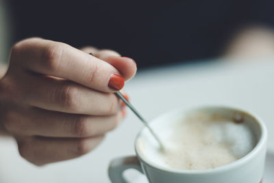 Close-up of hand holding coffee cup / spoon