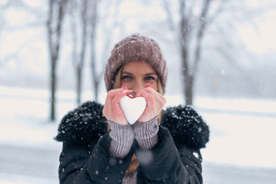 Portrait of woman covering face with snow