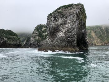 Rock formation in sea against clear sky