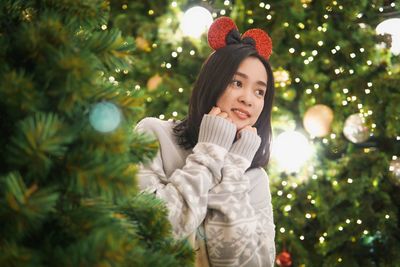 Portrait of woman standing by christmas tree