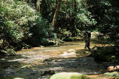 Man and woman walking on rocks in forest