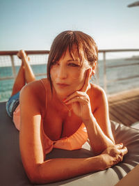 Portrait of woman sitting by sea against sky