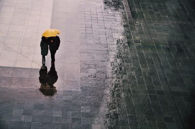 High angle view of friends with umbrella while walking on wet street during monsoon