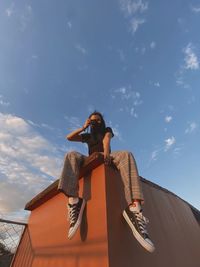 Low angle view of woman sitting against sky