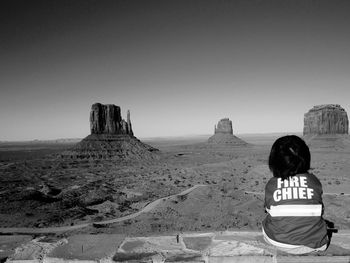 Rear view of child sitting against desert