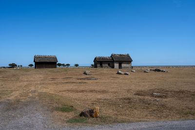 House on field against clear blue sky