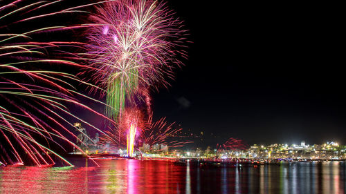 Firework display over river against sky at night