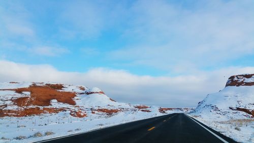 Empty road along snow covered landscape