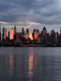 Sea by buildings against sky during sunset