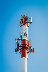 Low angle view of communications tower against clear blue sky