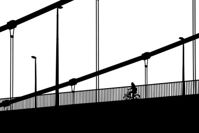 Silhouette people walking on bridge against clear sky