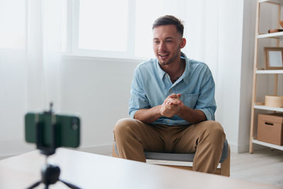 Portrait of young man using mobile phone at home