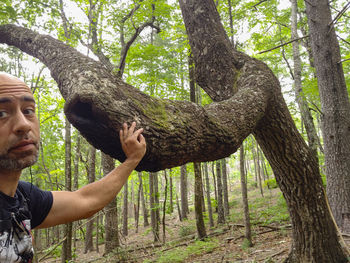 Portrait of man with tree trunk in forest