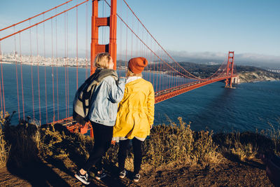 Rear view of woman standing on suspension bridge