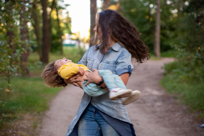 Mother playing with daughter while standing outdoors