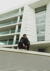 Low angle view of man sitting on staircase of building