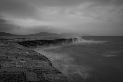 Long exposure of lyme regis pier in dorset in black and white