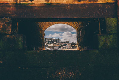 Building against sky in city seen through arch