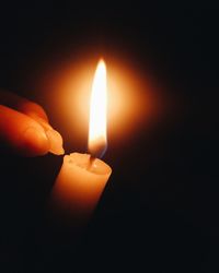 Close-up of lit candle in darkroom