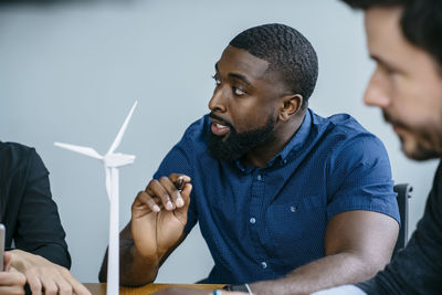 Business people working on wind turbine model during meeting in office