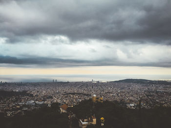 Aerial view of city against cloudy sky