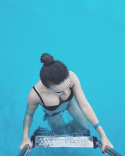 Directly above shot of young woman on ladder in swimming pool