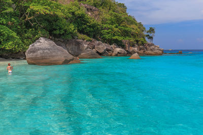 Scenic view of rocks by sea against sky