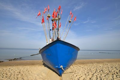 Ship moored on beach against sky