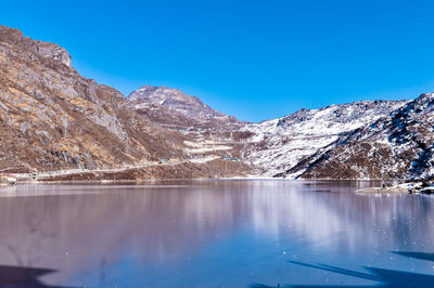 Scenic view of lake and snowcapped mountains against blue sky