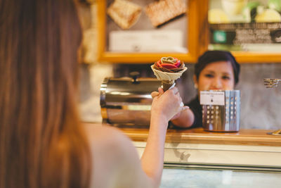 Portrait of woman holding ice cream in cafe