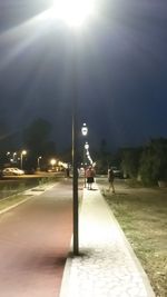 Illuminated street light on road in city at night