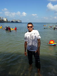 Portrait of man standing in sea against sky