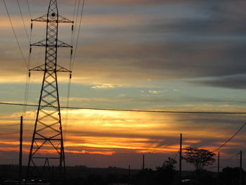 Silhouette electricity pylon against dramatic sky