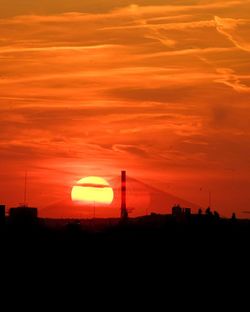 Silhouette electricity pylon against dramatic sky during sunset