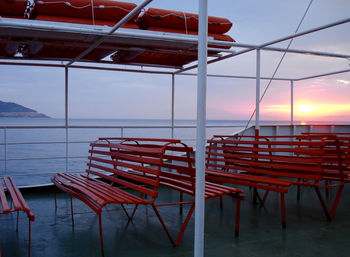 Empty chairs and table against sea during sunset